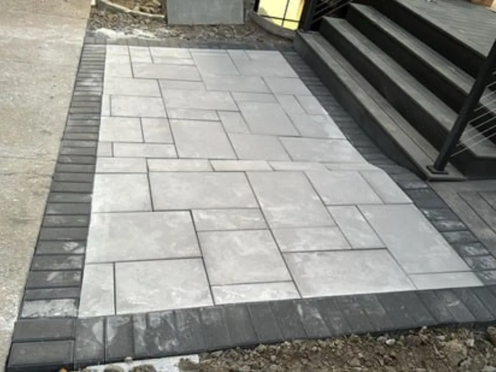Patio paver installation showing detailed stonework beside stairs.