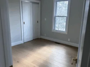 Bedroom Renovation featuring a newly installed window, white trim, and minimalist finishes.